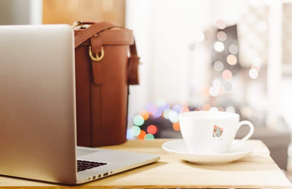 coffee mug, laptop and brown bag